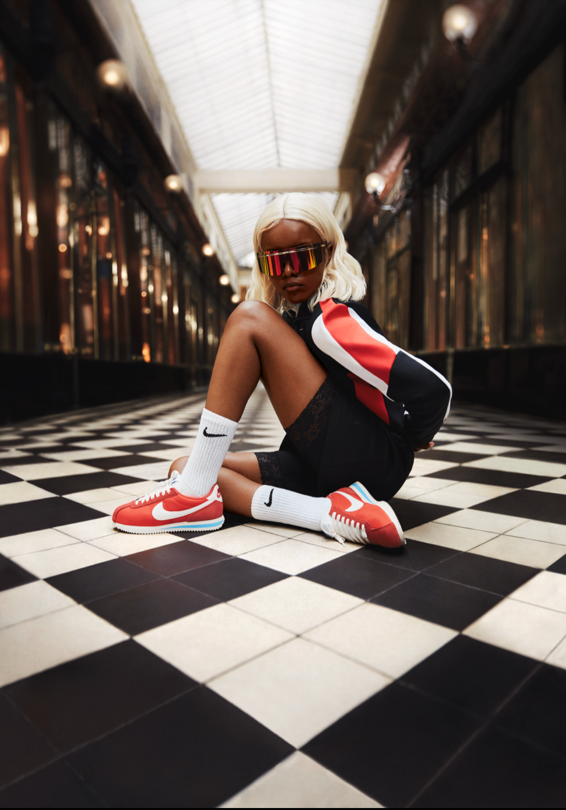 Editorial portrait of a model in a classic arcade wearing red Nike Cortez sneakers
